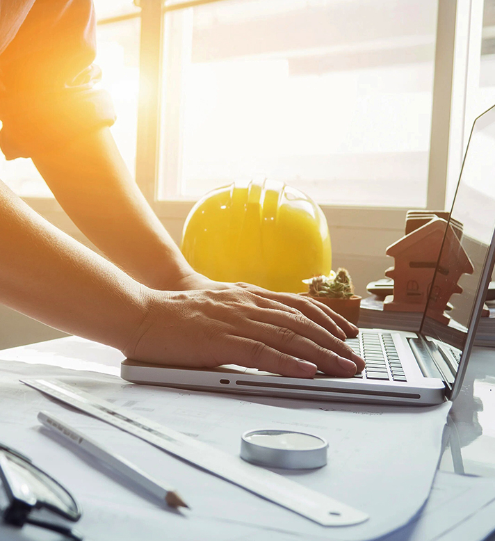 Construction project planning with hard hat, laptop and blueprints